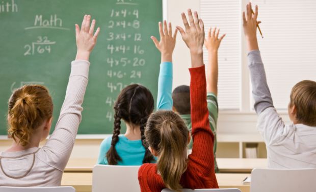 students in class with hands raised